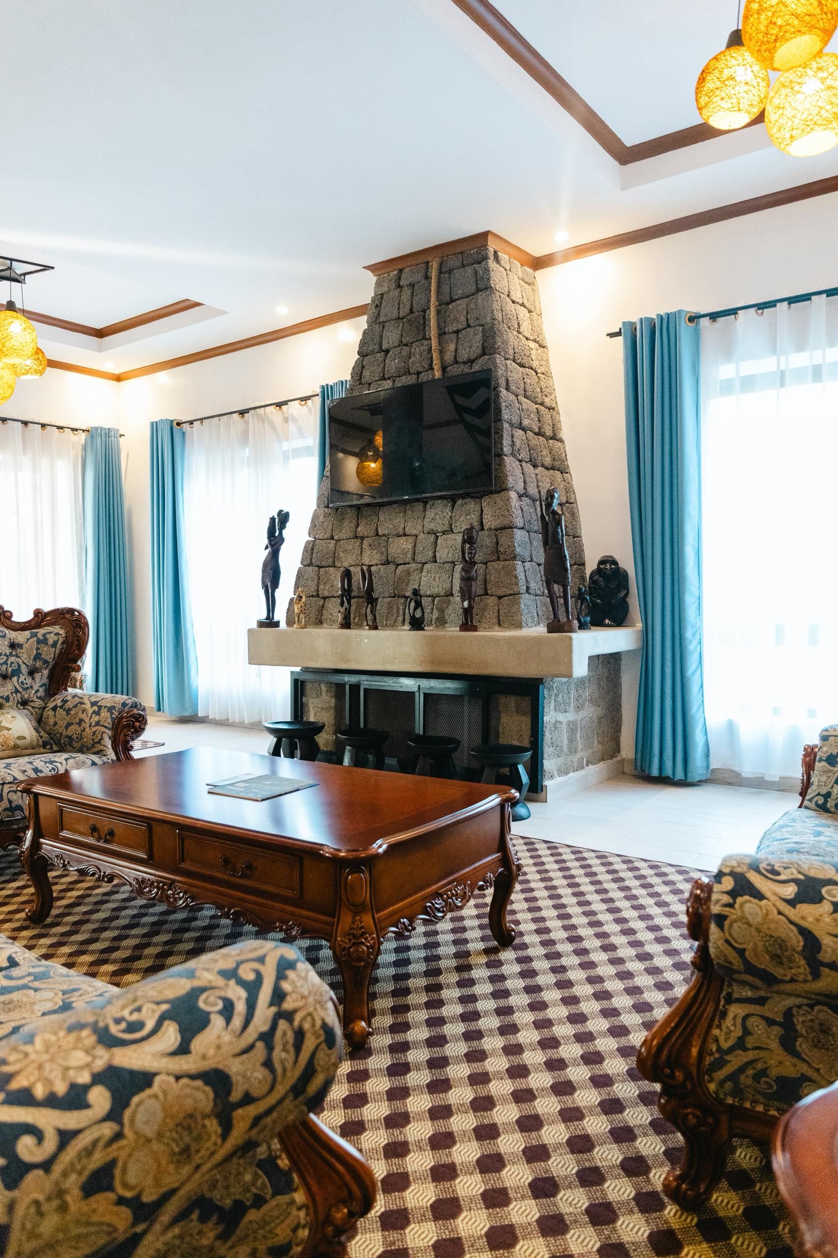A living room with a stone fireplace, patterned sofas, and a coffee table.