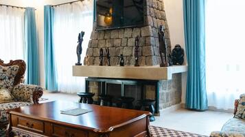 A living room with a stone fireplace, patterned sofas, and a coffee table.