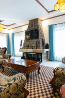 A living room with a stone fireplace, patterned sofas, and a coffee table.