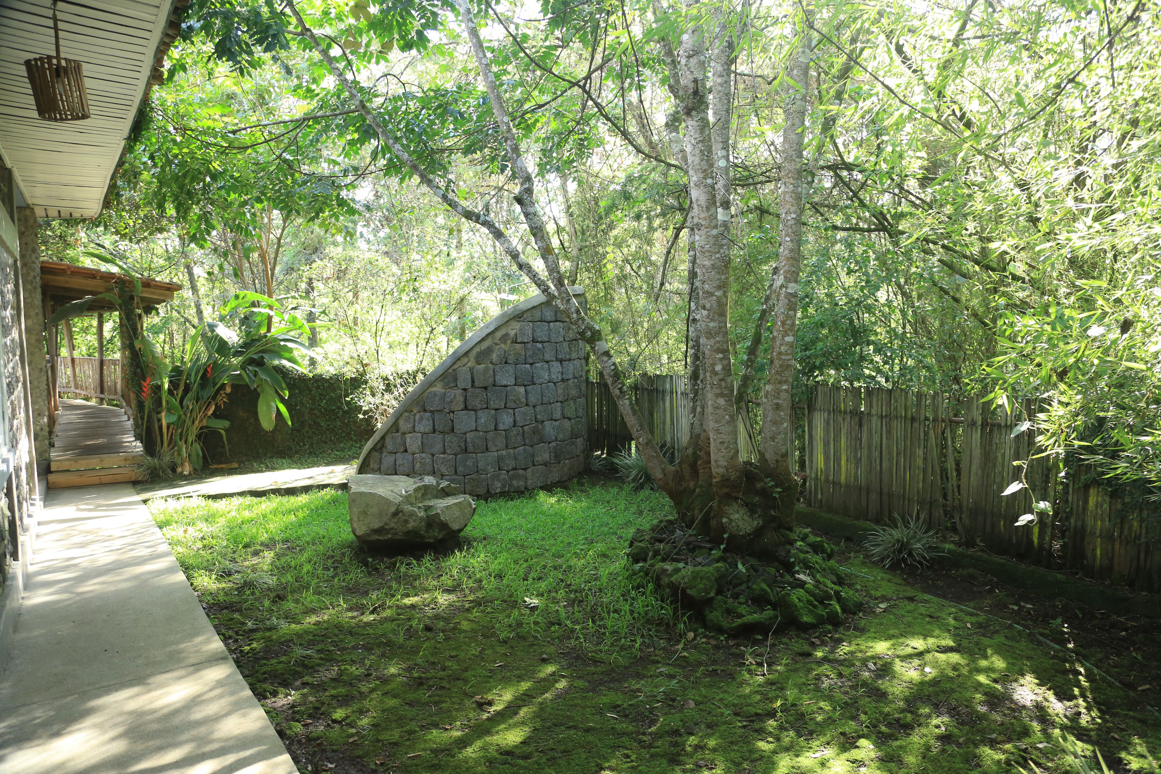 A stone wall, a wooden deck, and a grassy yard with trees.