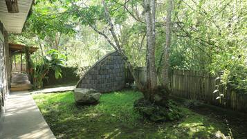 A stone wall, a wooden deck, and a grassy yard with trees.
