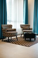 Una sala de estar con dos sillones estampados y un reposapiés negro sobre una alfombra con diseño.