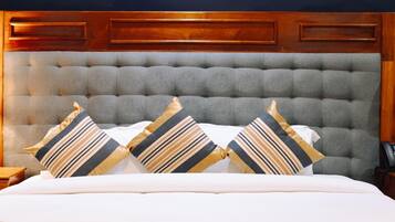 Une chambre à coucher avec une tête de lit capitonnée, un lit agrémenté d’oreillers à rayures et trois œuvres d’art encadrées accrochées au mur.