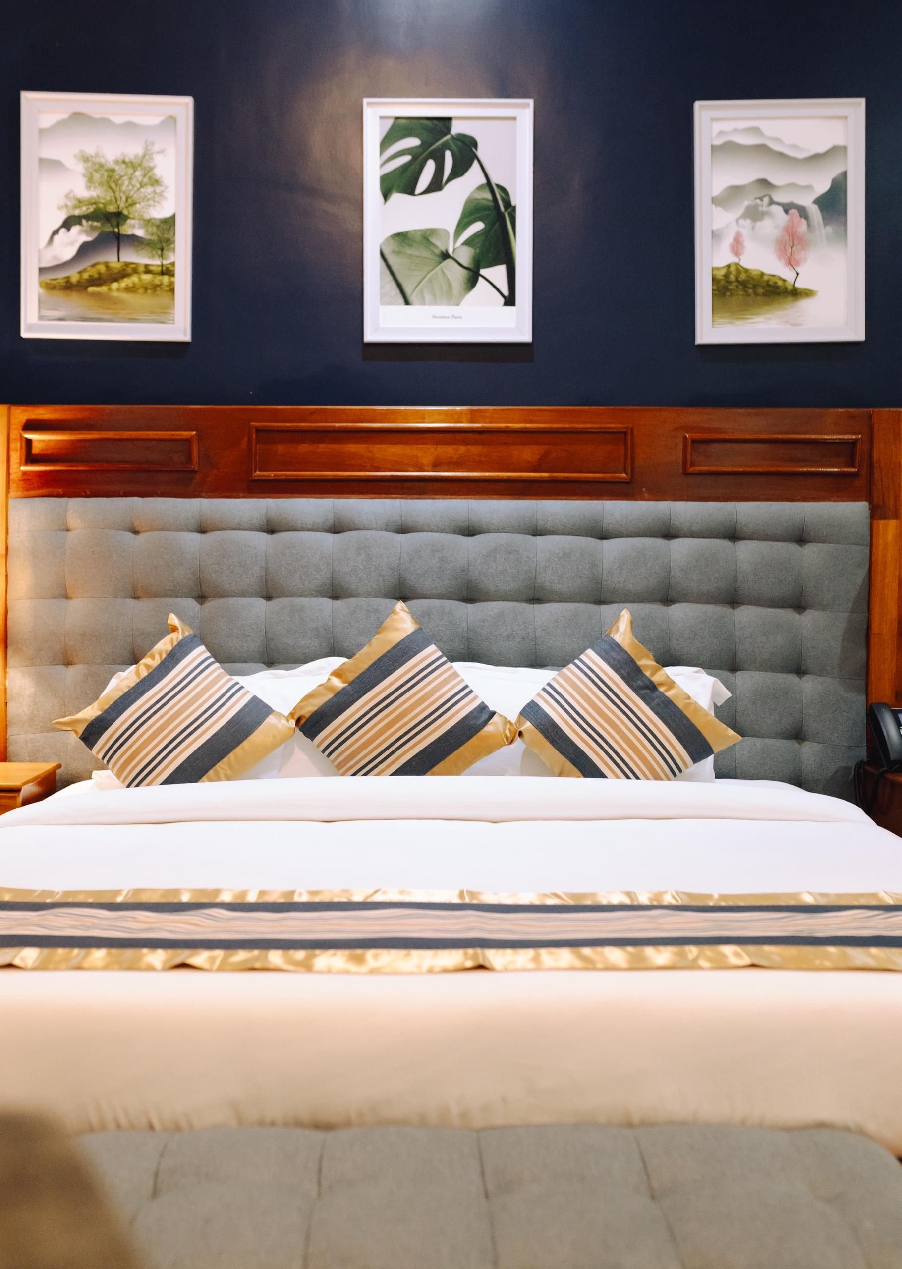 A bedroom with a tufted headboard, a bed with striped pillows, and framed artwork on the wall.