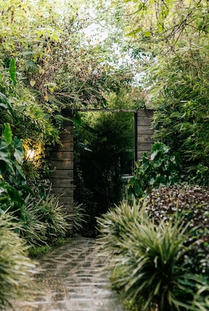 Un sendero estrecho que atraviesa un exuberante jardín con una puerta de madera.