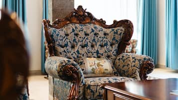 A room with a patterned sofa, a wooden coffee table, and a view of a building outside.