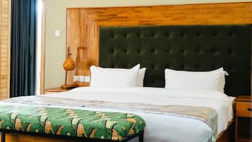 Habitación de hotel con una cama grande, cabecera de madera, suelo a cuadros y puerta de madera.