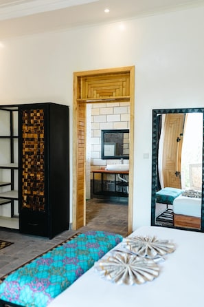 Un interior moderno con un armario de madera, un banco estampado y vistas a una habitación con escritorio y cama.