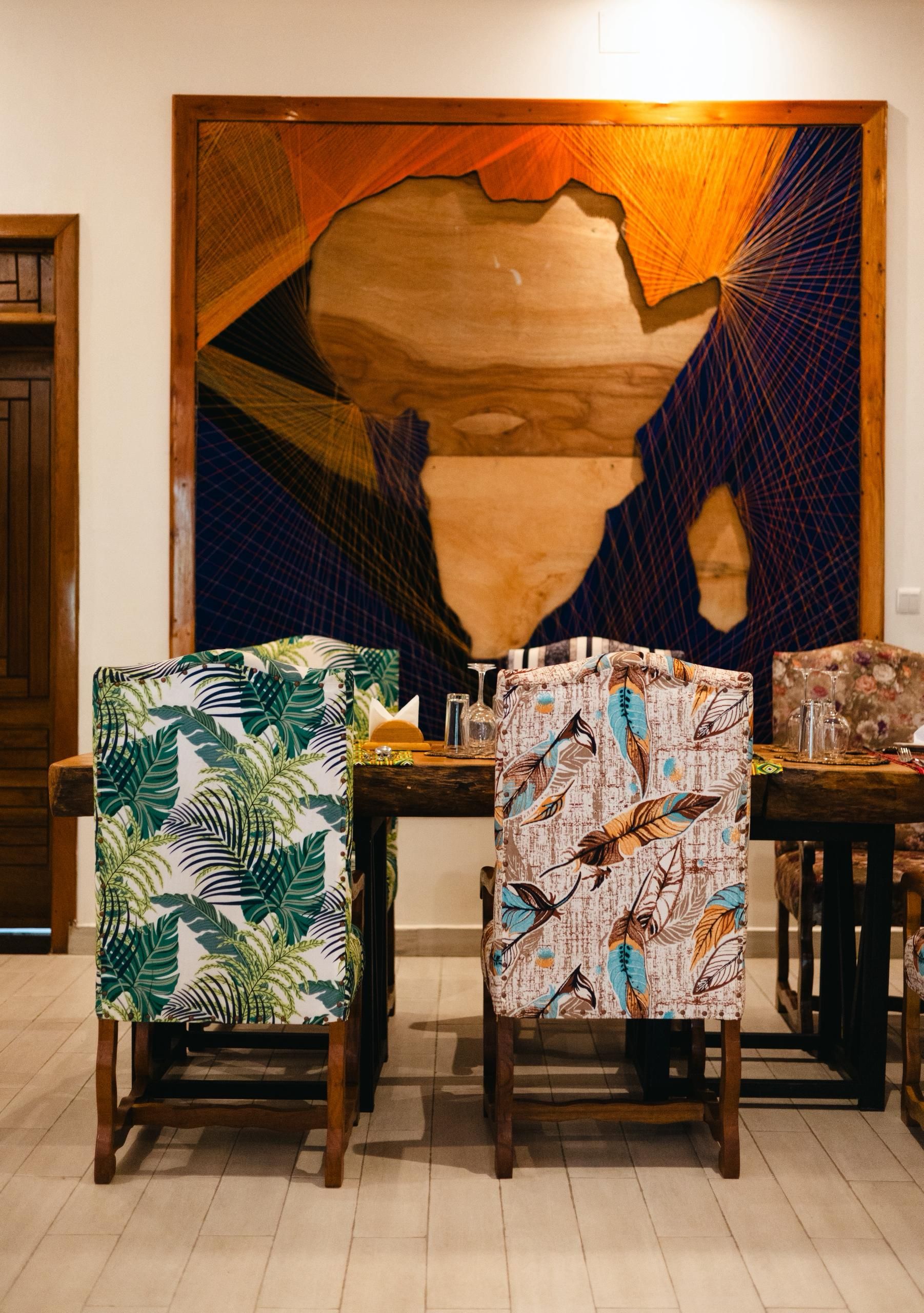 A dining area with two chairs, a table, and a large abstract painting on the wall.