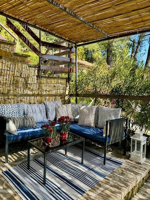 An outdoor seating area with a bamboo ceiling, a blue sofa with patterned cushions, and a striped rug. - Apartment with pool and views of medieval Gubbio (Gubbio)
