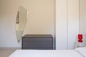 A bedroom with a bed, a dresser, a mirror, and a red lamp on a nightstand. - Villa Andrews by Wonderful Italy (Bari)
