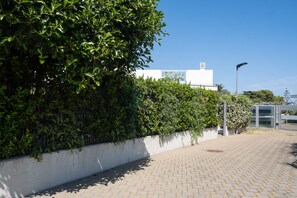 A paved walkway with a hedge on one side and a building in the background. - Villa Andrews by Wonderful Italy (Bari)