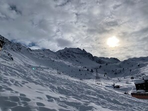 Paisaje nevado de montaña con un telesilla y un edificio.