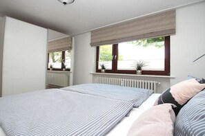A bedroom with a bed, a window with a view, and a radiator. - Holiday apartment in Sylt with 3 bedrooms (Sylt \/ OT Westerland)