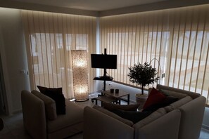 Un salon moderne avec un canapé, une table basse, un téléviseur et une lampe sur pied.