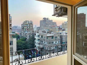 A balcony with a view of a densely built urban area, featuring multiple buildings and a clear sky. - 3BRs Bohimian Citycenter Apartmemt (Cairo Governorate)