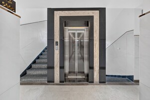 An elevator entrance with a marble frame, a stairway to the left, and a sign above indicating '500s'.