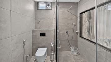 Un baño moderno con cabina de ducha de vidrio, un inodoro y un bidé.
