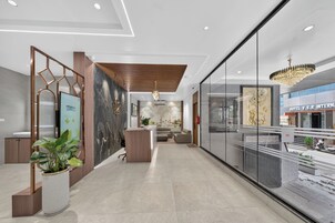 A modern hotel lobby with a reception desk, seating area, and a view of the street.