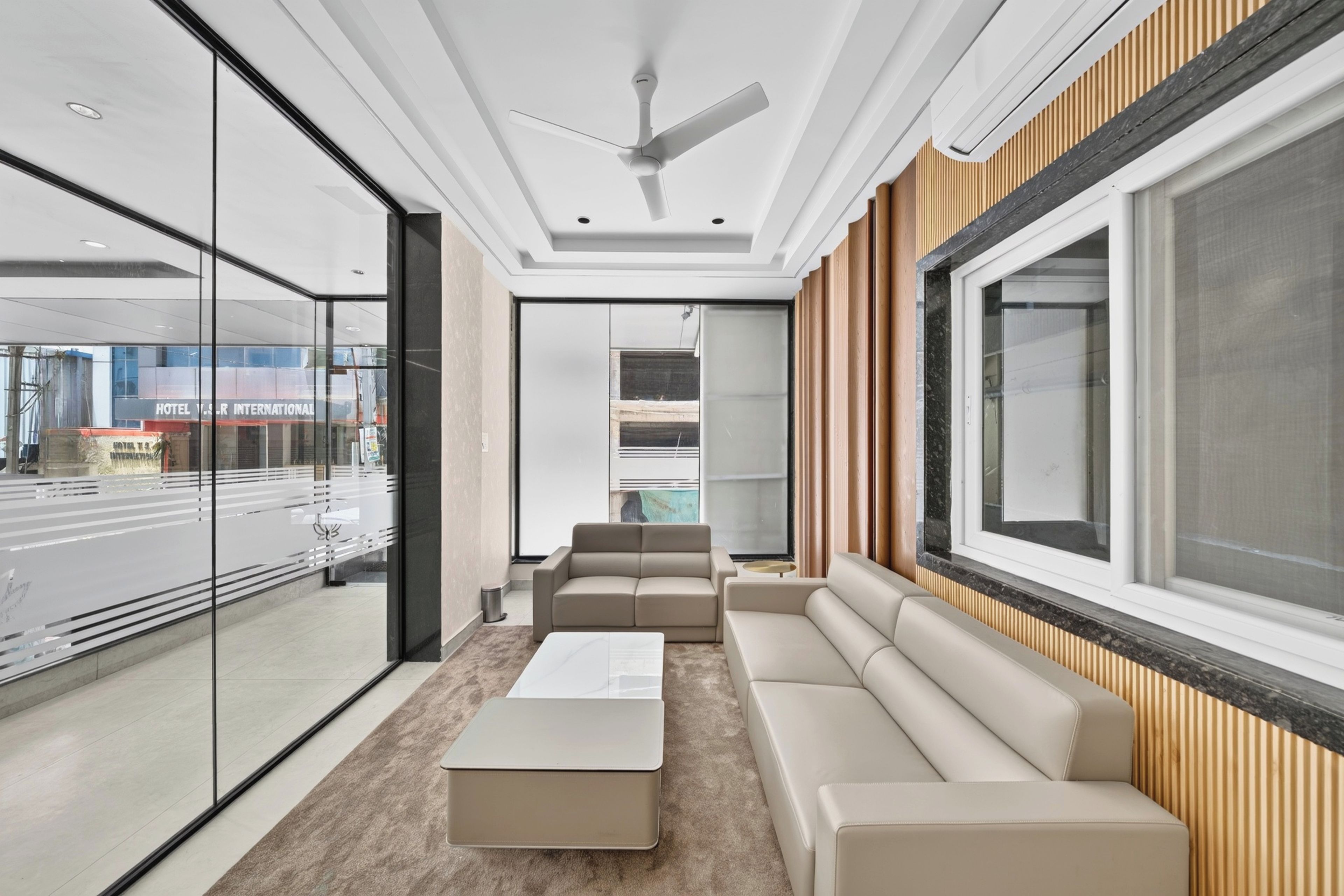 Ein modernes Hotelzimmer mit großem Fenster, Deckenventilator, Sofa und Couchtisch.