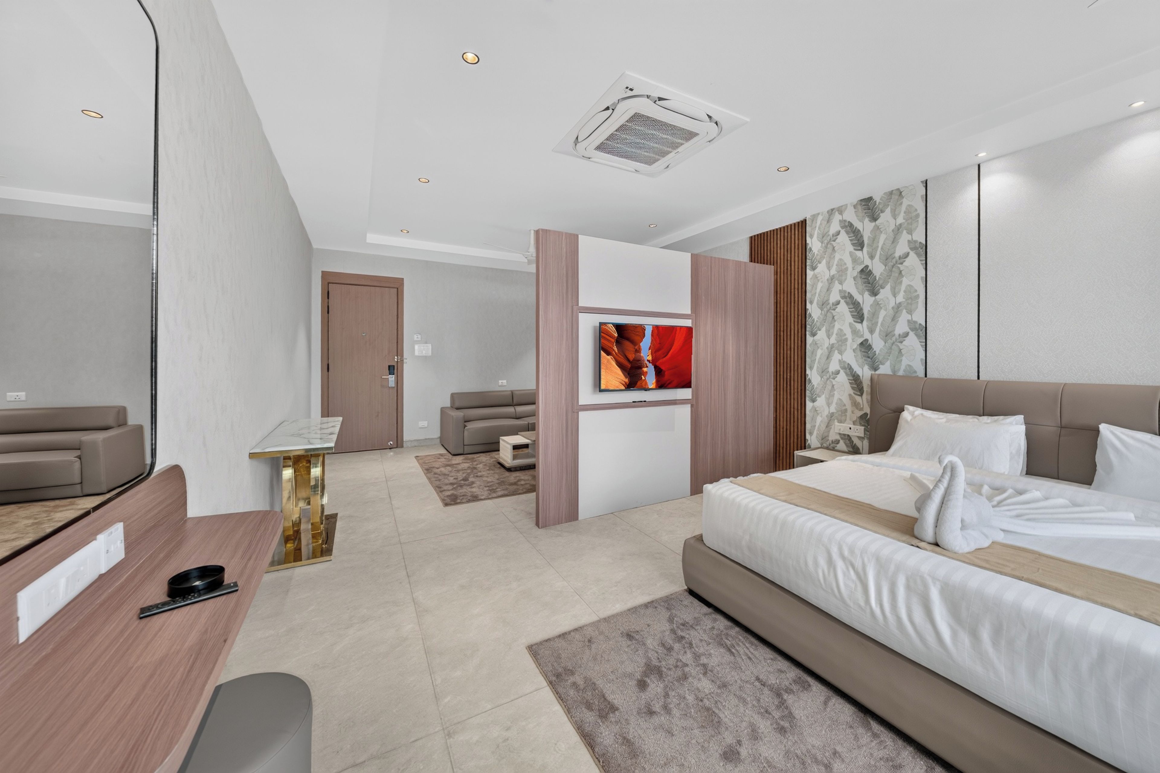 Moderni hotellihuone, jossa on sänky, työpöytä, sohva ja televisio.