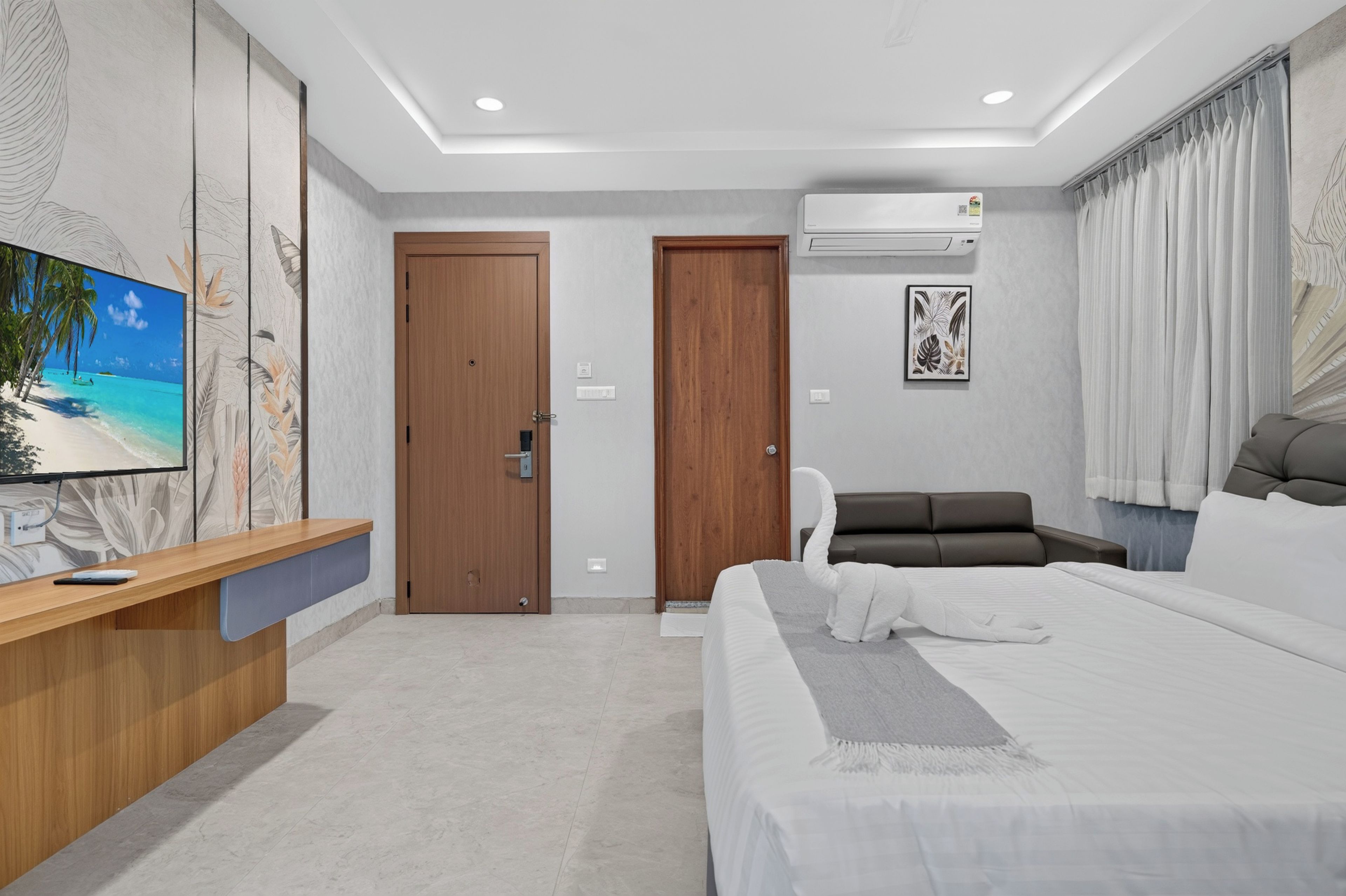 Una habitación de hotel moderna con cama, escritorio, televisor y sofá.