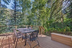 An outdoor deck with a table and chairs, surrounded by dense forest. - Spring Hill Hideaway - Vail (Vail)