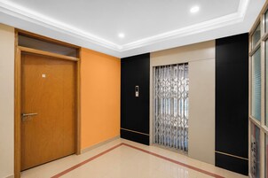 Un pasillo con una puerta de madera, una pared negra y beige, y una ventana con una reja de metal.