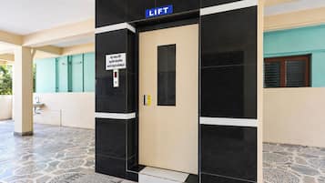 A lift door with a sign indicating a lift, a pull handle, and a floor with patterned tiles.
