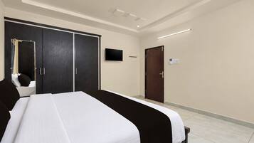 A hotel room with a large bed, a wardrobe, a television, and a door.