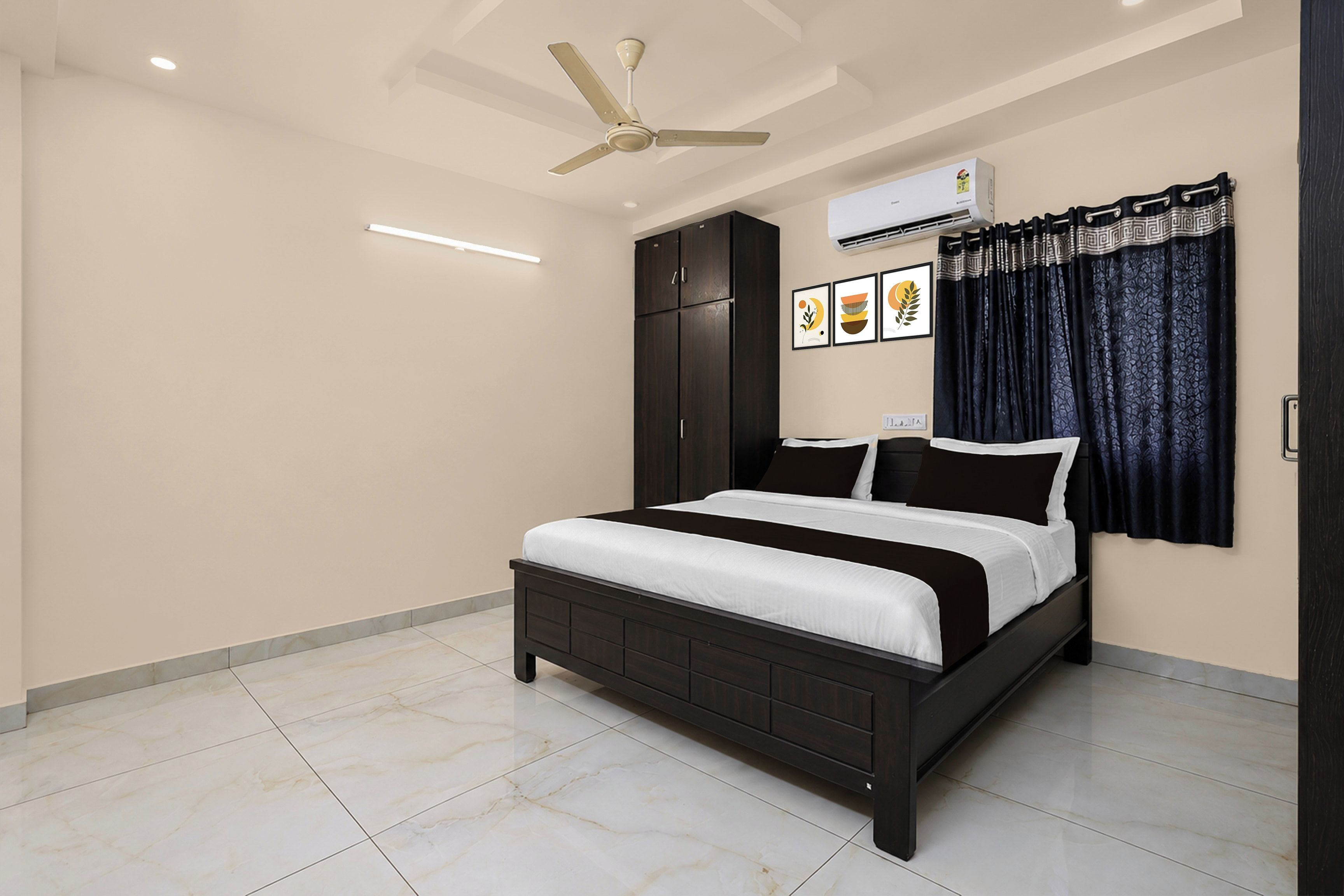 A bedroom with a bed, dark wooden wardrobe, ceiling fan, air conditioning unit, and a window with curtains.