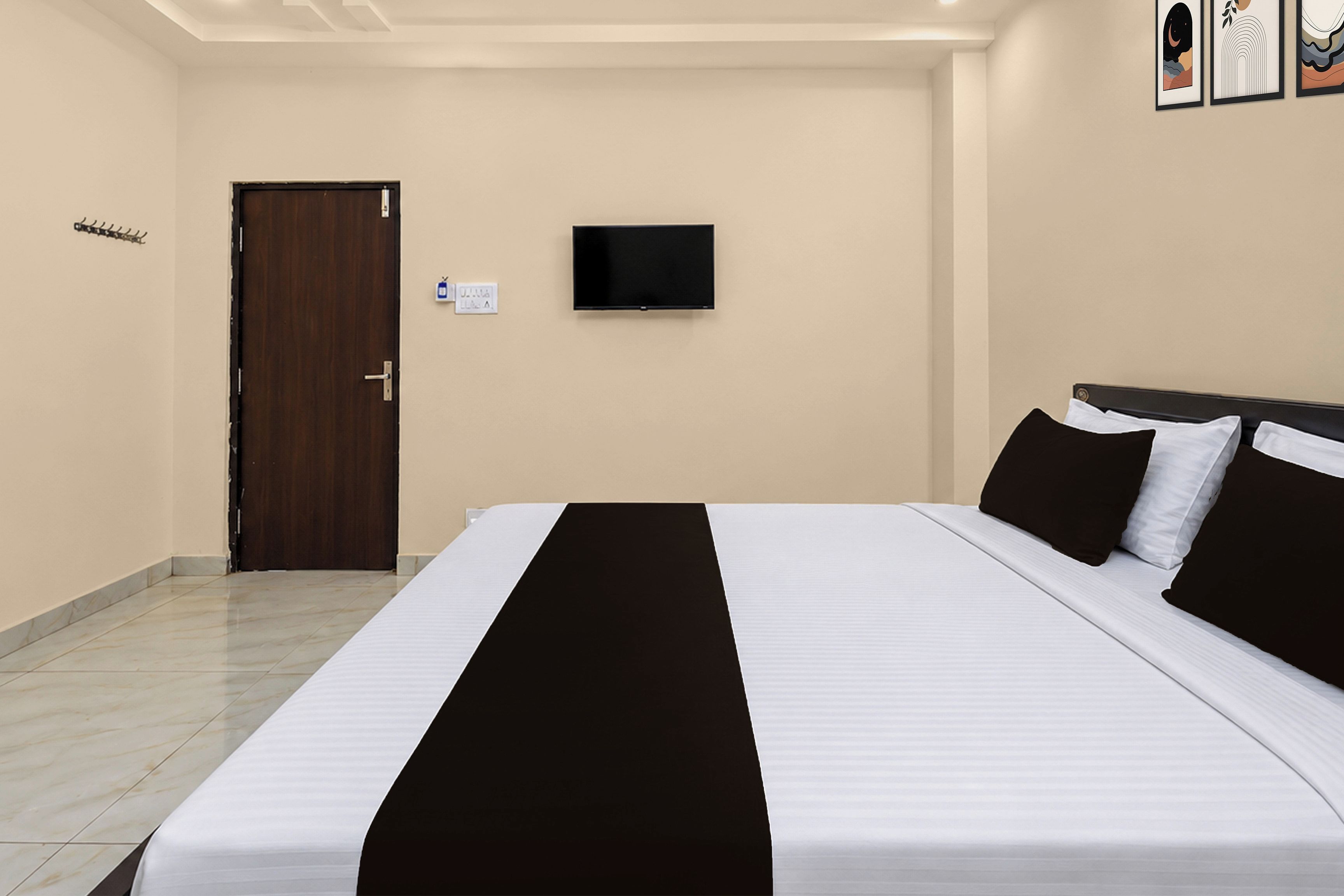 A hotel room with a bed, a television mounted on the wall, and a door.