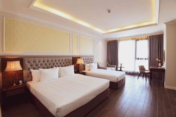 A hotel room with two beds, a sitting area, and a view of the outdoors.
