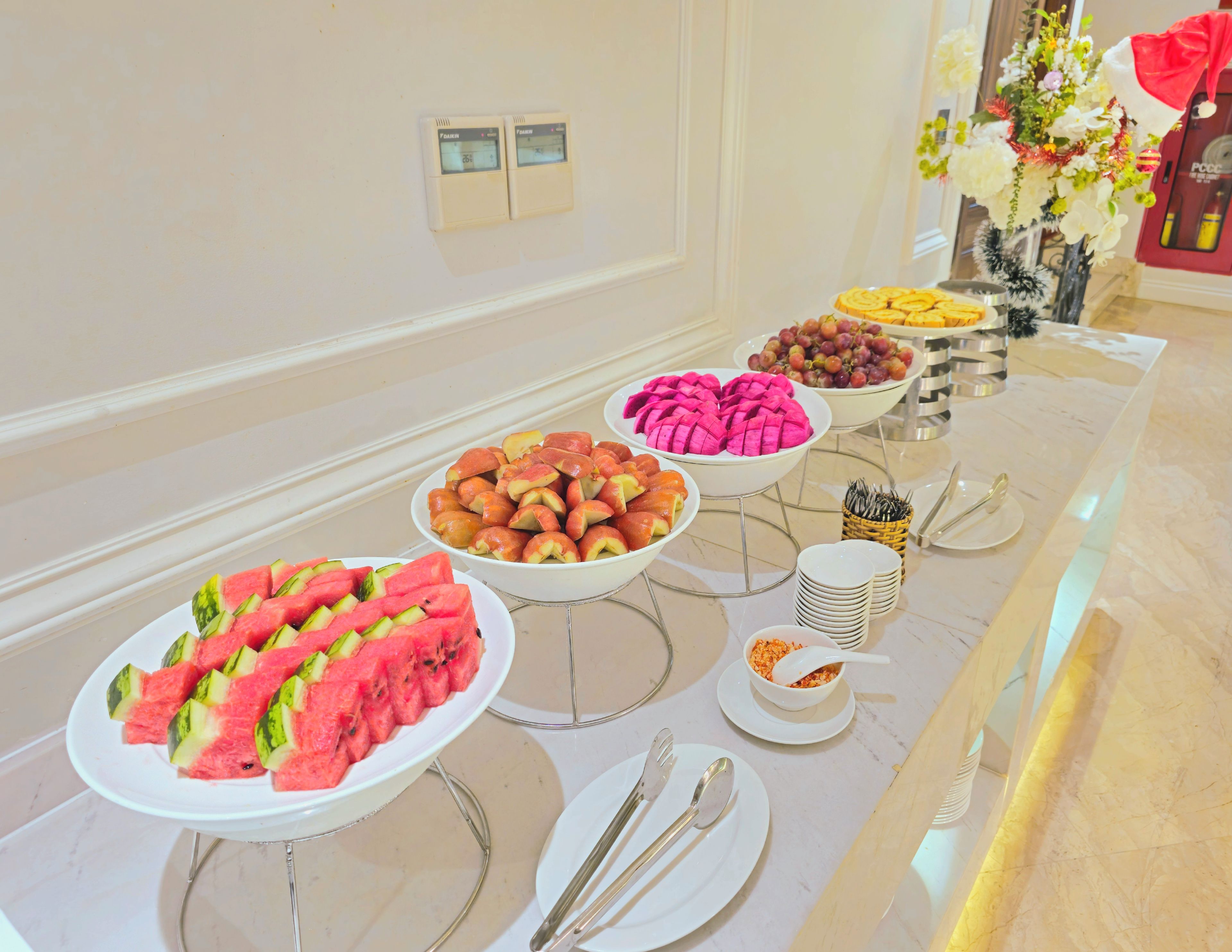 A buffet table with various fruits and a decorative vase.
