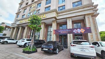 A hotel with a prominent entrance, a large sign, and several parked cars in front.