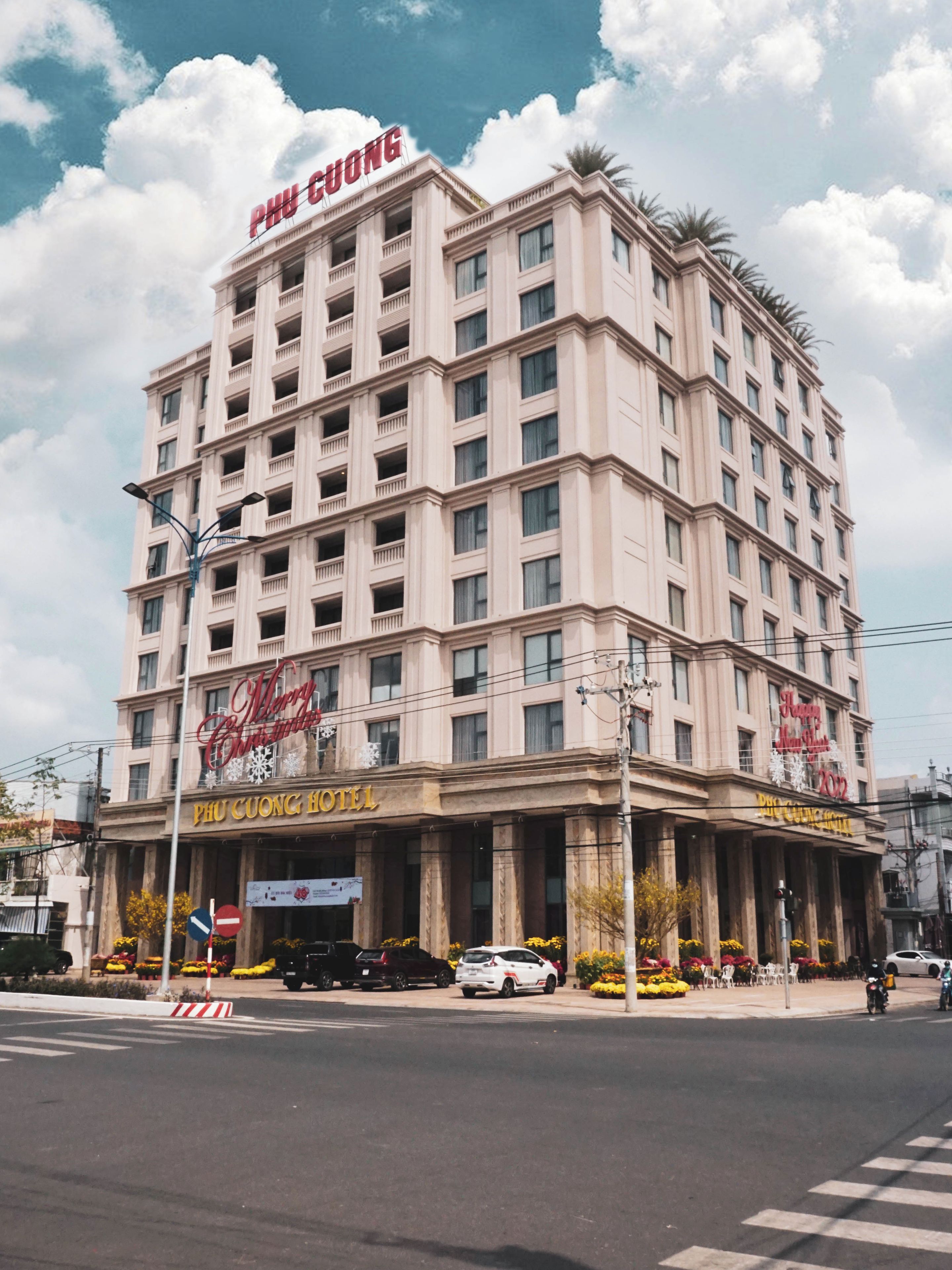 A multi-story hotel with a prominent sign reading 'PHU CUONG HOTEL' and 'Merry Christmas'.