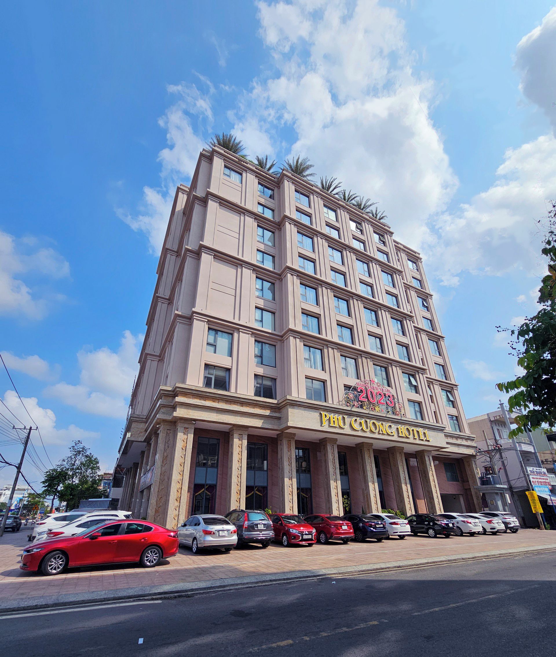 A multi-story hotel with a prominent sign for 'Phi Cuong Hotel' and a 'Happy New Year 2023' banner.