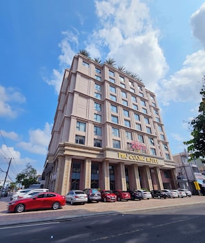 Un hotel de varios pisos con un letrero llamativo que dice 'Phi Cuong Hotel' y un banderín con la inscripción 'Feliz Año Nuevo 2023'.