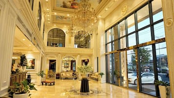 A grand lobby with a chandelier, large windows, and a polished floor.