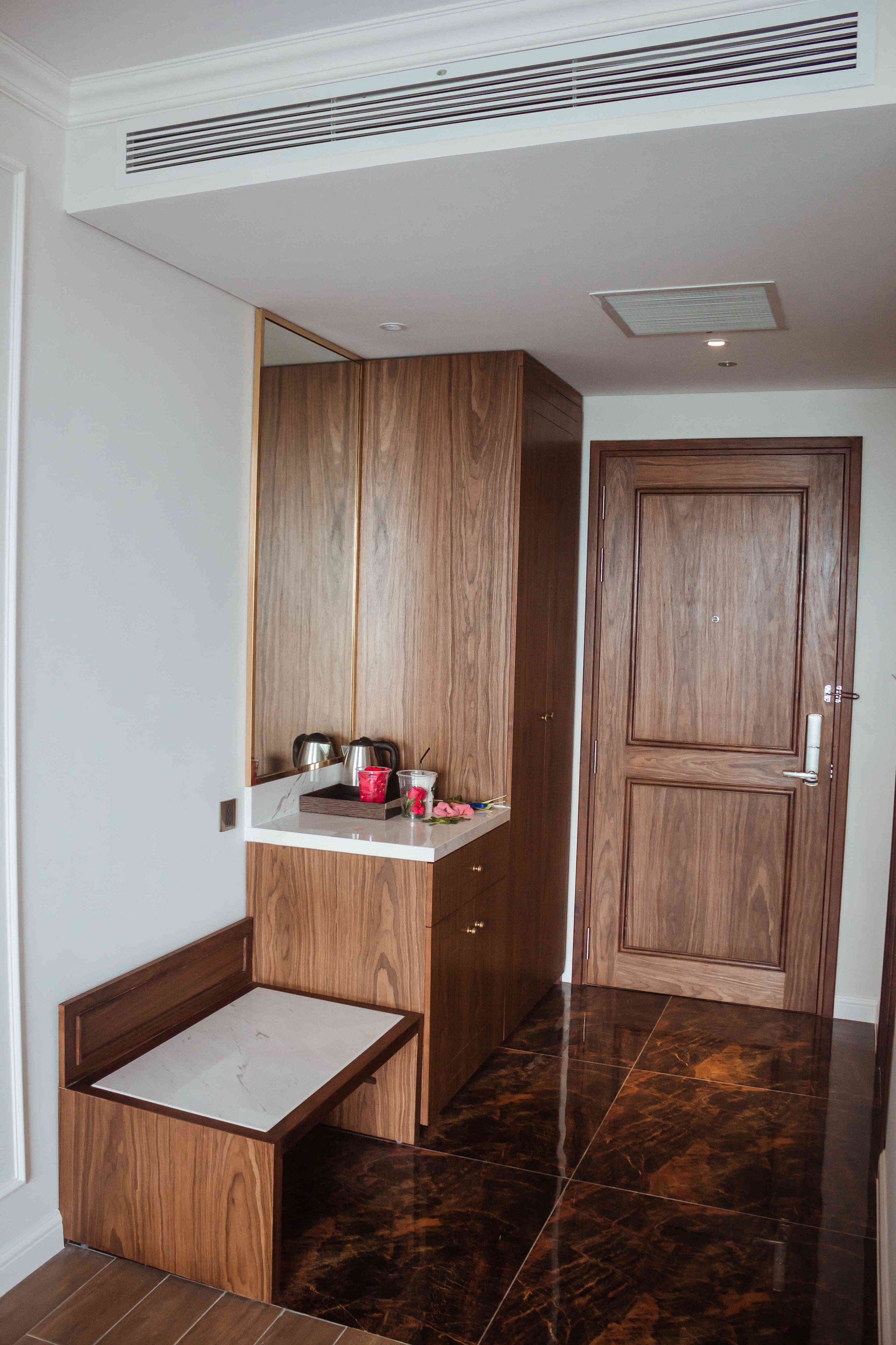 A bathroom with a wooden vanity, a mirror, a sink, and a door.
