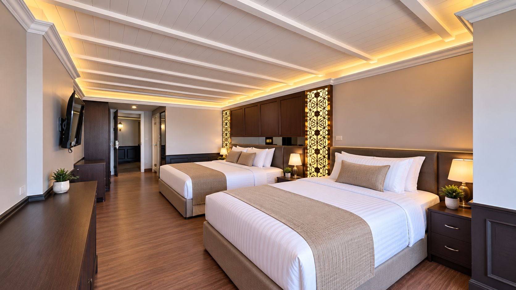 A hotel room with two beds, a TV, a desk, and a decorative wall panel.
