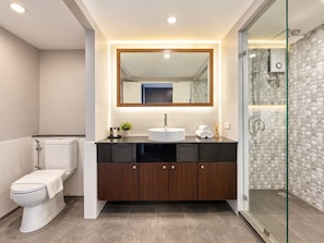 Une salle de bain moderne comprenant des toilettes, un meuble-lavabo avec un miroir et un espace douche.