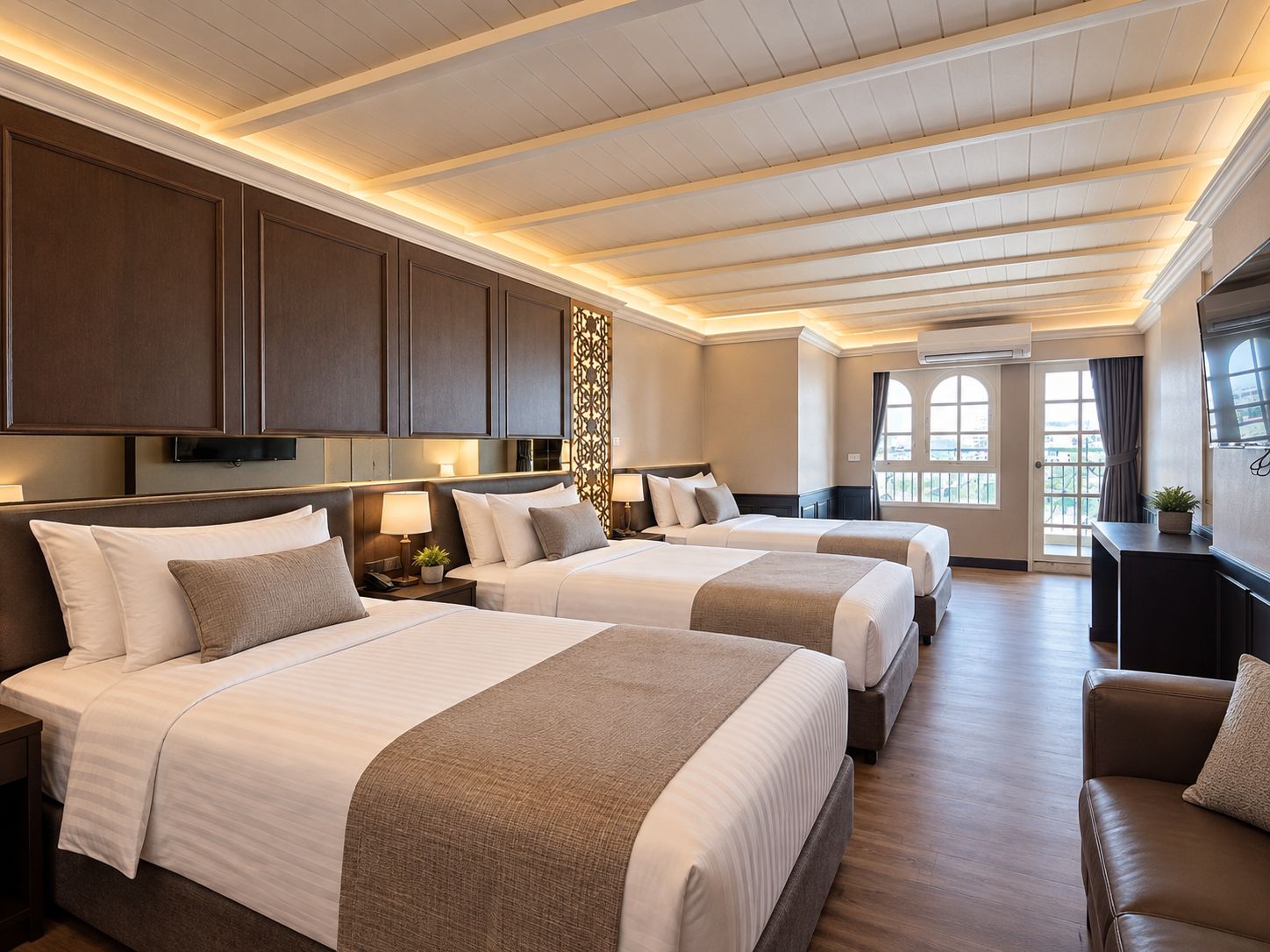 A hotel room with two beds, a sofa, a TV, and a window with a view.