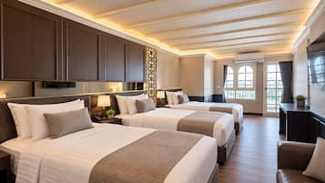 A hotel room with two beds, a sofa, a TV, and a window with a view.