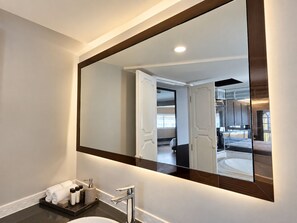 Un baño moderno con un espejo grande, un lavamanos y un perchero para toallas.