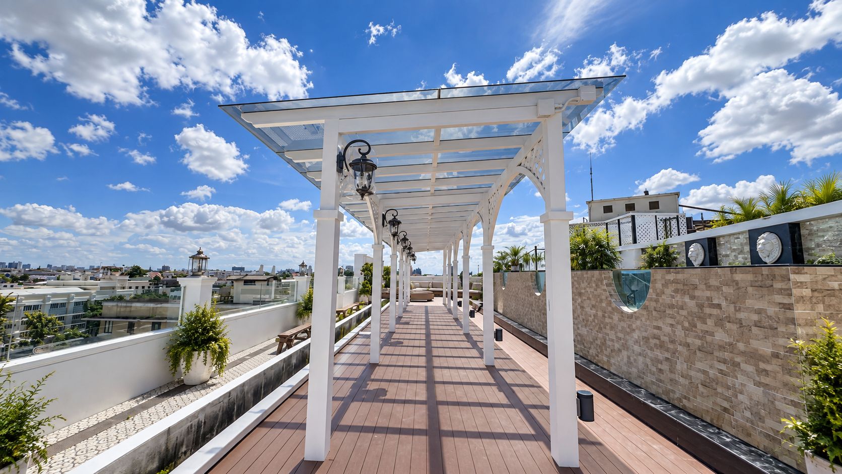 A covered outdoor walkway with a tiled floor, white columns, and potted plants.