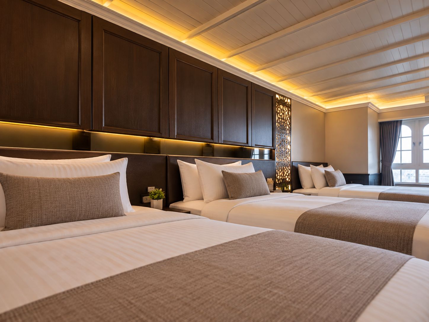 A hotel room with two beds, dark wood paneling, and a decorative wall feature.
