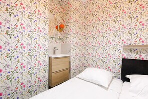 A bedroom with a bed, a nightstand, a mirror, and a wall with floral wallpaper. - 3 Chambres 2 SDB Balcon Garage A3b139 (Cannes)