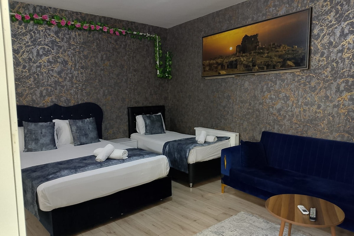 Un dormitorio con dos camas, un sofá azul, un cuadro y una mesita redonda.
