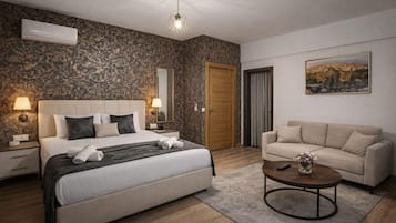 Een hotelkamer met een bed, een bank, een bijzettafeltje, een schilderij en een deur.